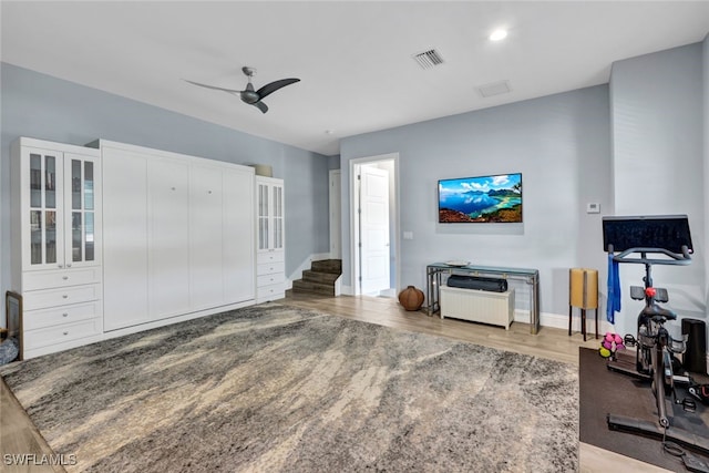 exercise area with ceiling fan and light hardwood / wood-style flooring