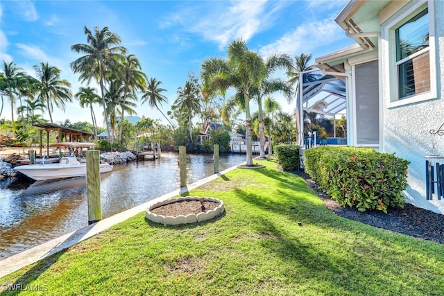 view of yard featuring glass enclosure, a water view, and a dock