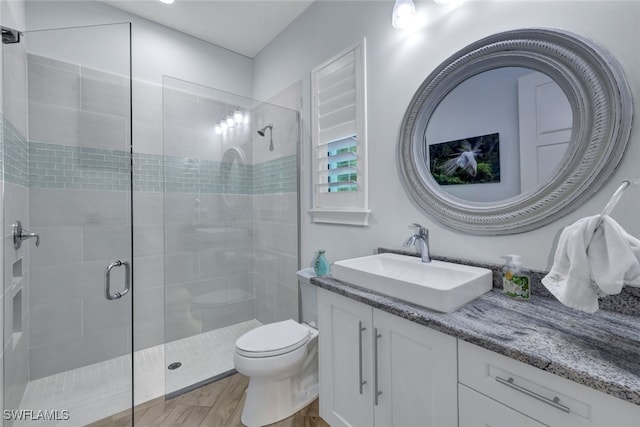 bathroom with a shower with shower door, vanity, and toilet