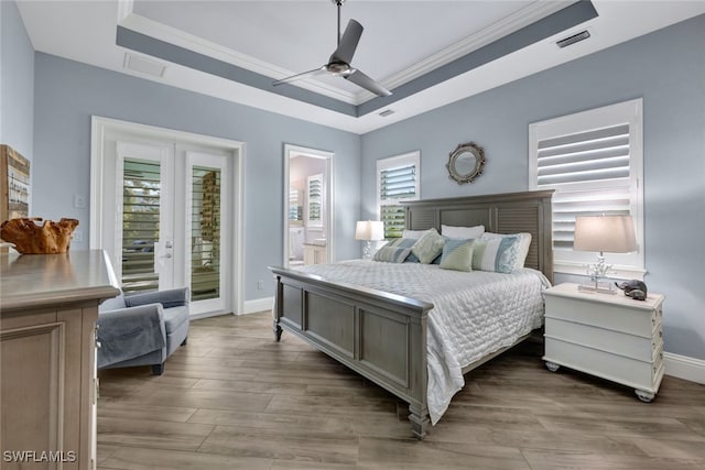 bedroom featuring ceiling fan, access to outside, a tray ceiling, and multiple windows