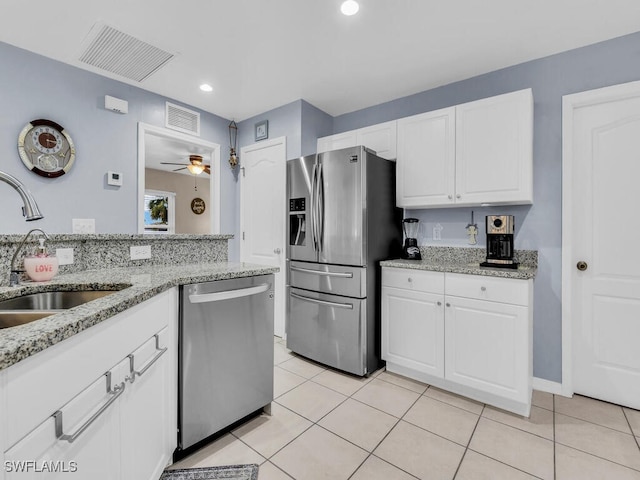 kitchen featuring ceiling fan, appliances with stainless steel finishes, light tile patterned flooring, white cabinets, and light stone counters