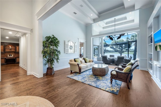 living room featuring crown molding, a towering ceiling, dark hardwood / wood-style flooring, and built in features