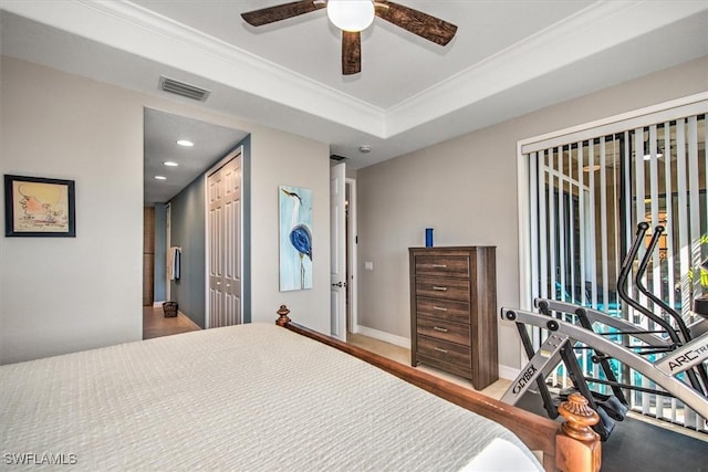 bedroom featuring crown molding, ceiling fan, a tray ceiling, and a closet