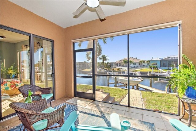 sunroom featuring a water view and ceiling fan