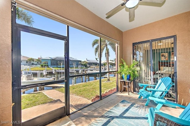 sunroom / solarium featuring a water view and ceiling fan