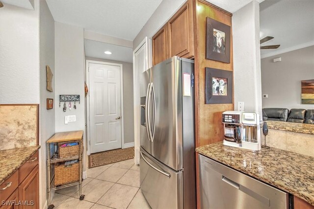 kitchen featuring stainless steel appliances, light tile patterned flooring, light stone countertops, and crown molding