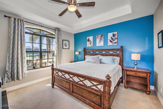 carpeted bedroom featuring crown molding, ceiling fan, and a raised ceiling