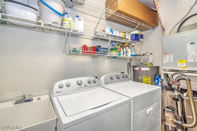 washroom with sink, water heater, and washing machine and clothes dryer