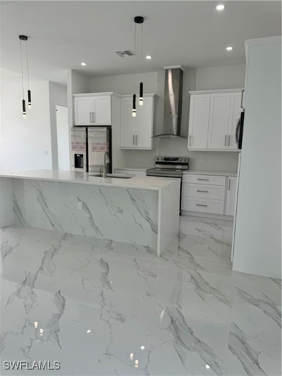 kitchen featuring sink, pendant lighting, white cabinetry, and wall chimney range hood