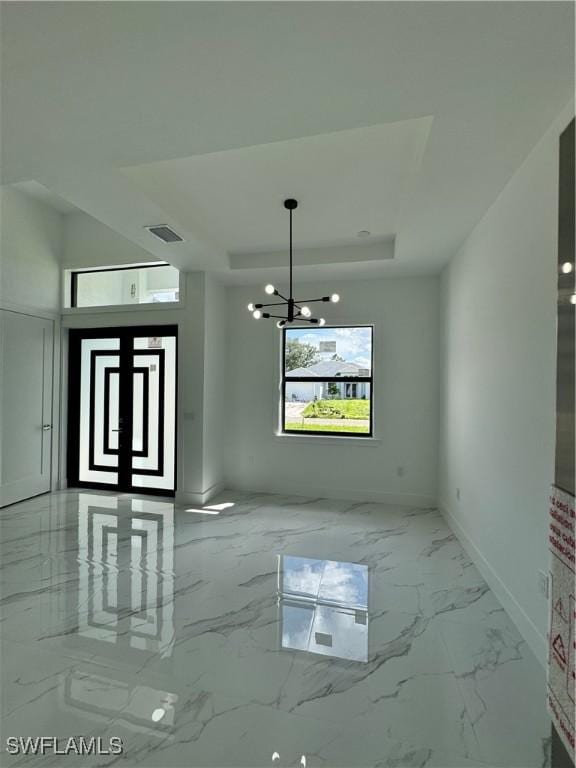 unfurnished dining area featuring an inviting chandelier and a tray ceiling