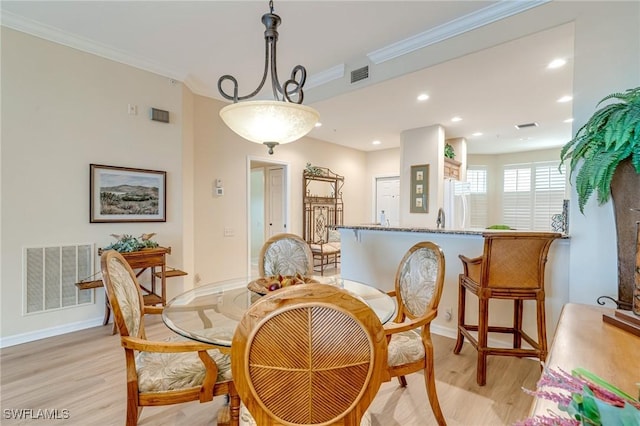 dining space featuring crown molding and light hardwood / wood-style flooring