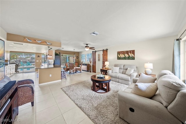 living room featuring ceiling fan, light tile patterned floors, and a barn door