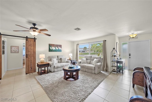 tiled living room with ceiling fan and a barn door