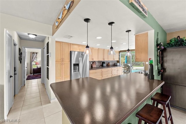 kitchen with backsplash, pendant lighting, light tile patterned flooring, light brown cabinetry, and stainless steel fridge