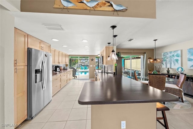 kitchen with stainless steel fridge with ice dispenser, a kitchen breakfast bar, light tile patterned flooring, light brown cabinetry, and pendant lighting