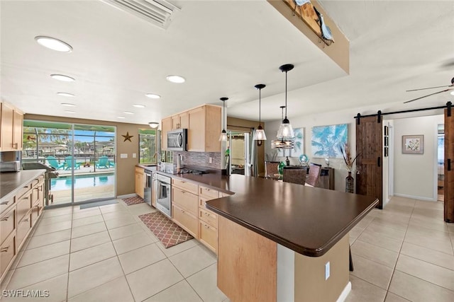 kitchen featuring light tile patterned floors, a barn door, appliances with stainless steel finishes, light brown cabinets, and backsplash