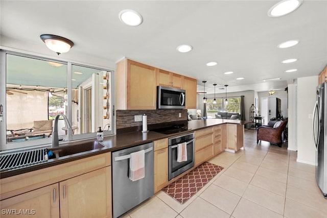 kitchen featuring sink, stainless steel appliances, light brown cabinetry, and decorative light fixtures