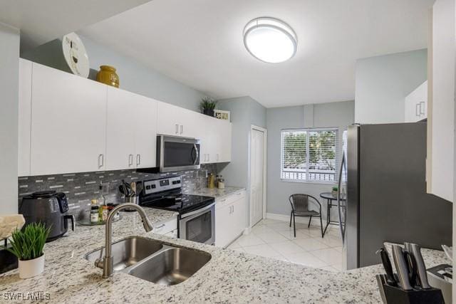 kitchen with sink, stainless steel appliances, white cabinetry, and decorative backsplash