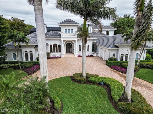 mediterranean / spanish-style home featuring a front lawn and glass enclosure