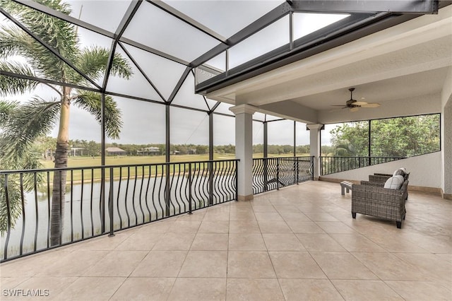 unfurnished sunroom with ceiling fan and a water view