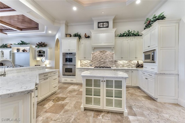 kitchen with white cabinets, appliances with stainless steel finishes, light stone counters, and a kitchen island