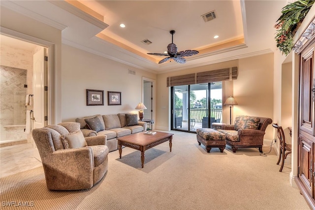 living room with ceiling fan, light colored carpet, crown molding, and a tray ceiling