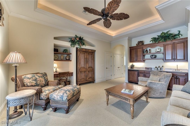 living room featuring ceiling fan, light colored carpet, a tray ceiling, and sink