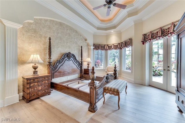 bedroom with ceiling fan, access to outside, crown molding, a tray ceiling, and light wood-type flooring