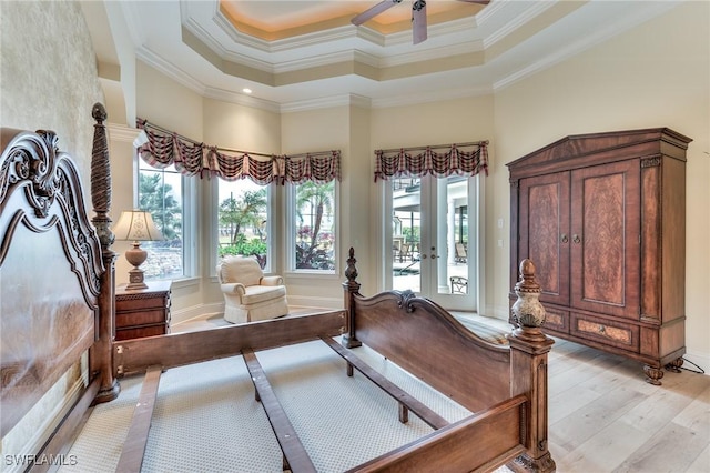 interior space featuring ceiling fan, light hardwood / wood-style floors, a raised ceiling, crown molding, and french doors