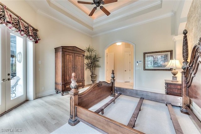 interior space featuring french doors, light wood-type flooring, ceiling fan, a tray ceiling, and crown molding