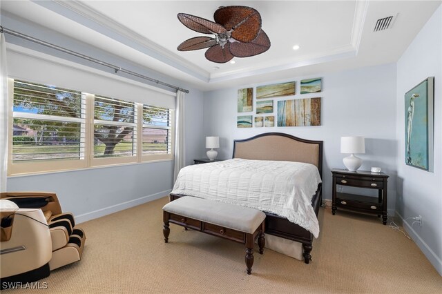 bedroom featuring light carpet, ceiling fan, ornamental molding, and a tray ceiling