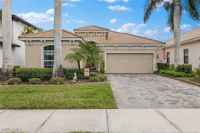 mediterranean / spanish home with a tile roof, a garage, stucco siding, a front yard, and decorative driveway