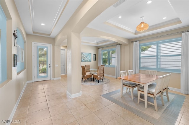 dining space with arched walkways, a tray ceiling, ornamental molding, and light tile patterned floors