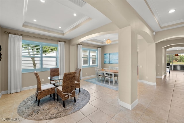 dining space with arched walkways, ornamental molding, light tile patterned floors, and a raised ceiling