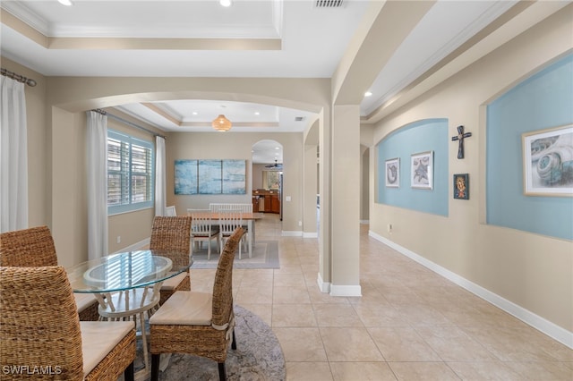 dining room with light tile patterned floors, a tray ceiling, and crown molding