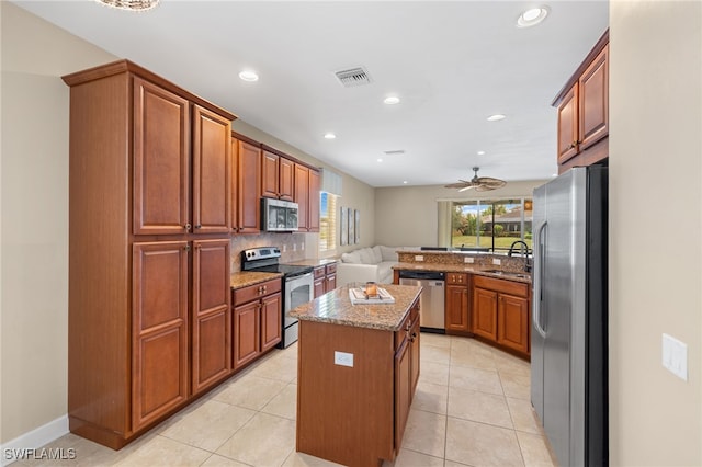 kitchen with a kitchen island, visible vents, a sink, light stone counters, and stainless steel appliances