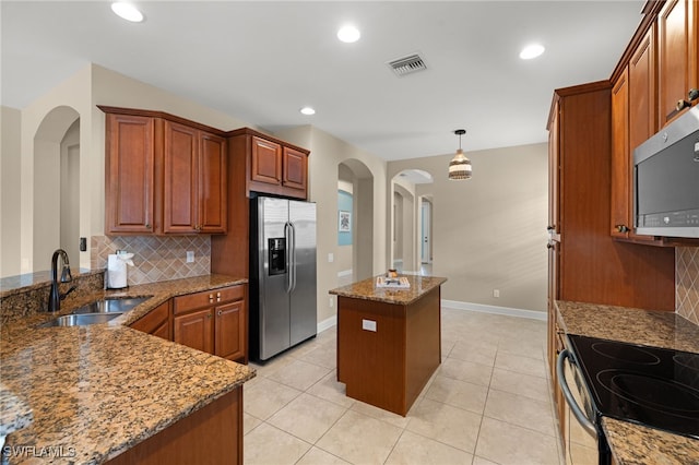 kitchen featuring appliances with stainless steel finishes, decorative backsplash, a center island, light stone countertops, and sink