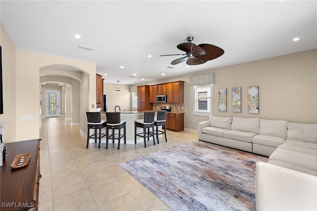 living area with visible vents, light tile patterned flooring, ceiling fan, recessed lighting, and arched walkways