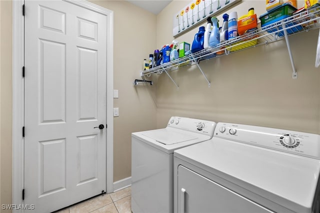 laundry area featuring laundry area, baseboards, washing machine and clothes dryer, and light tile patterned flooring