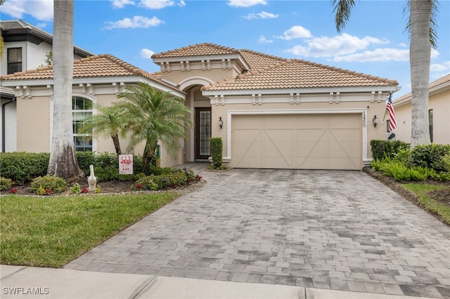 mediterranean / spanish-style home featuring decorative driveway, an attached garage, and stucco siding