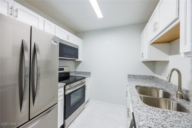 kitchen with light stone countertops, appliances with stainless steel finishes, white cabinetry, and sink