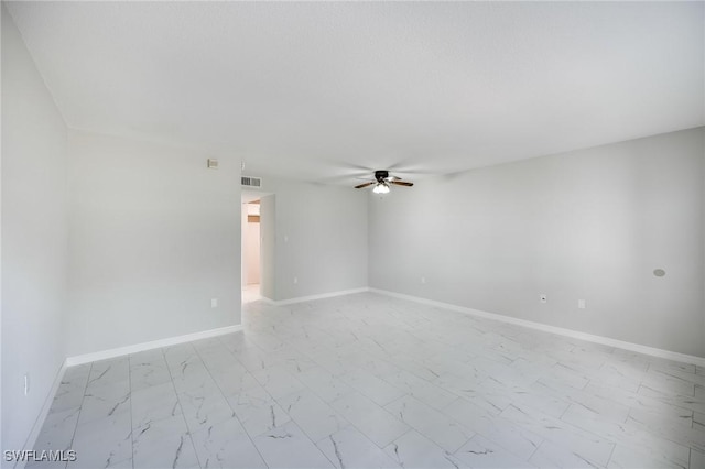 empty room featuring visible vents, baseboards, marble finish floor, and a ceiling fan