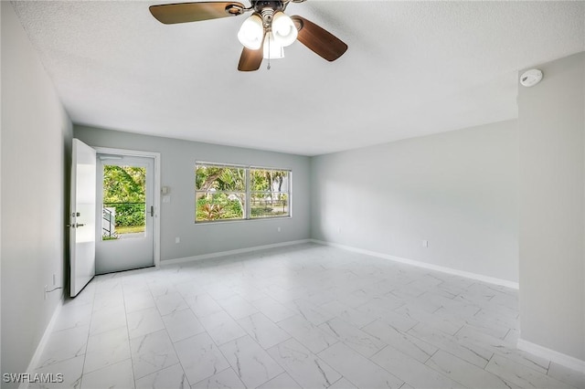 unfurnished room with baseboards, a textured ceiling, marble finish floor, and a ceiling fan