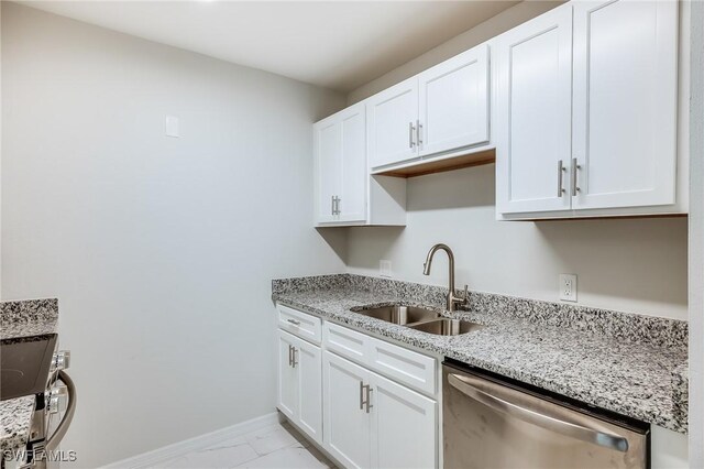 kitchen with appliances with stainless steel finishes, white cabinetry, light stone counters, and sink