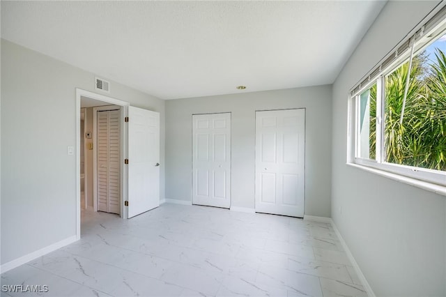 unfurnished bedroom featuring visible vents, baseboards, and marble finish floor