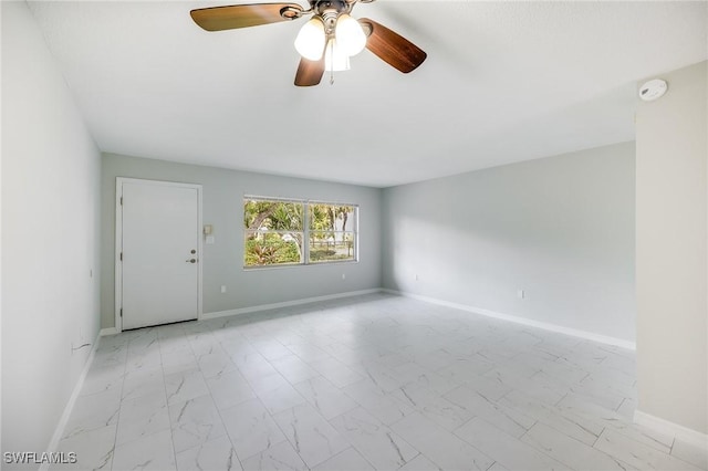 empty room featuring marble finish floor, baseboards, and ceiling fan