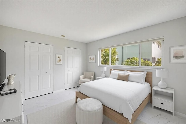 bedroom featuring marble finish floor, baseboards, and multiple closets