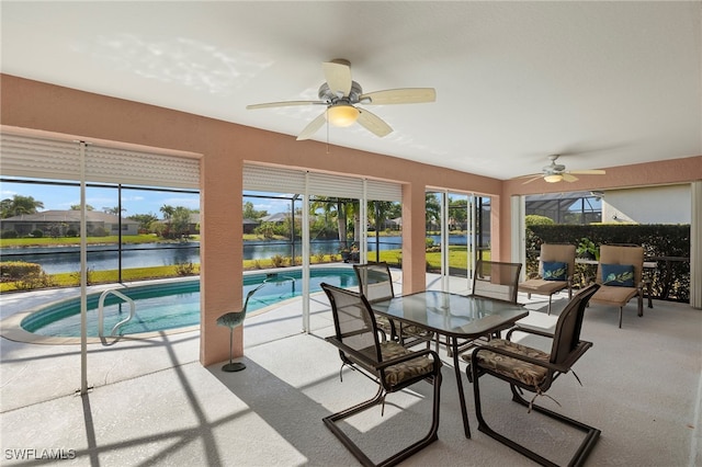 sunroom with a pool, ceiling fan, and a water view