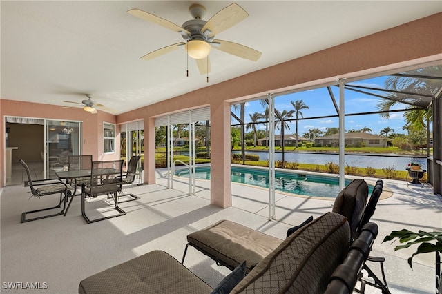 view of patio with a lanai, ceiling fan, and a water view