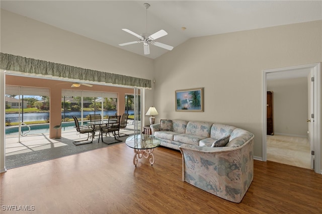 living room featuring lofted ceiling, hardwood / wood-style flooring, ceiling fan, and a water view